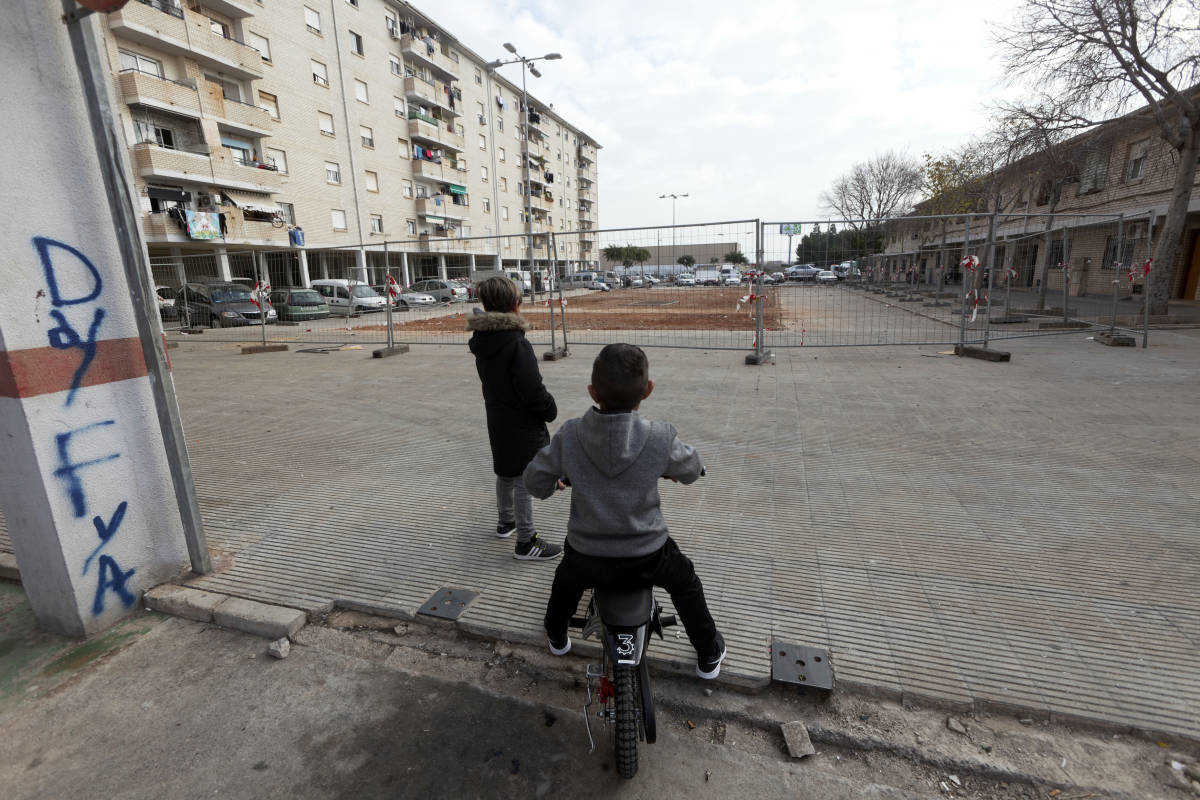 Dos niños observan la plaza vallada por las obras.
