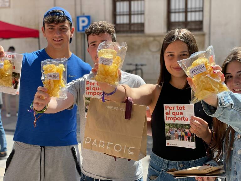 Tres jóvenes, con las bolsas en el punto informativo de la plaza Pescadería.